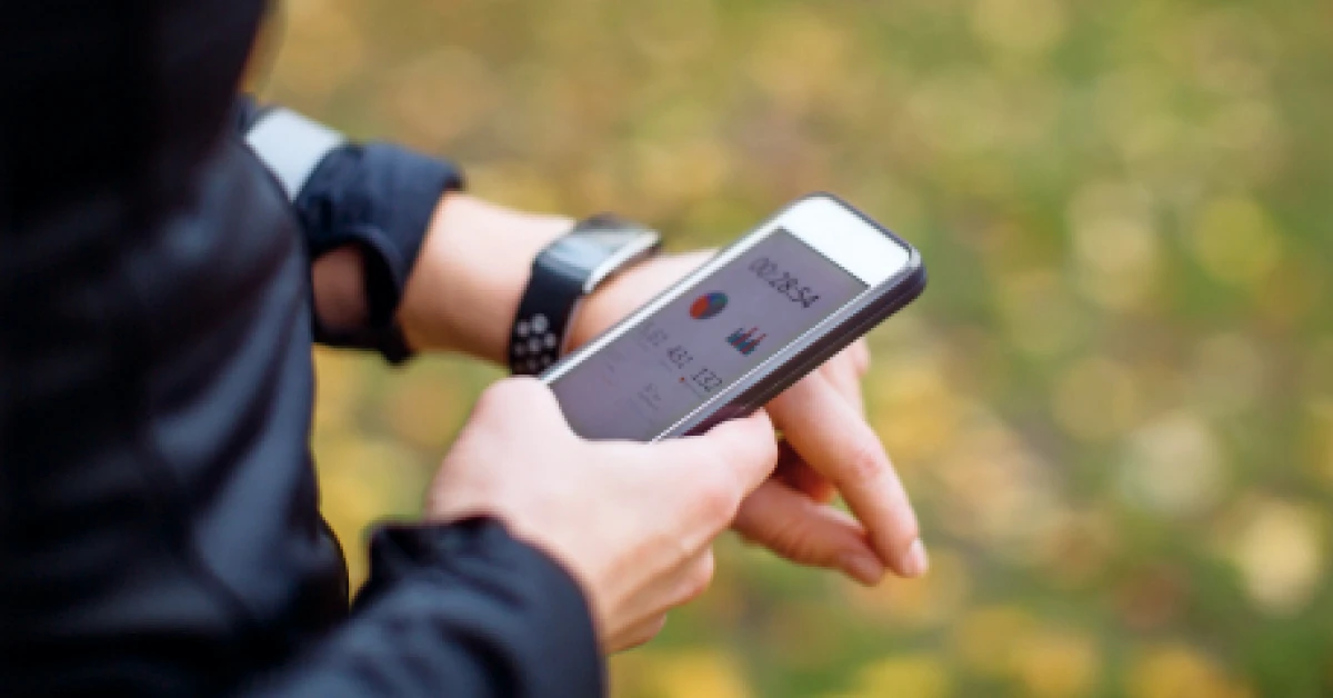 Close up of a urban runner using sporty smart watch and smartphone app.