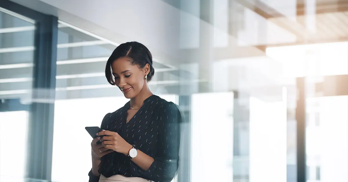 Woman smiling looking down at her phone.