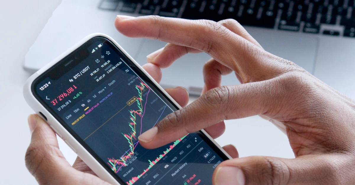 Person using smartphone to check financial markets.