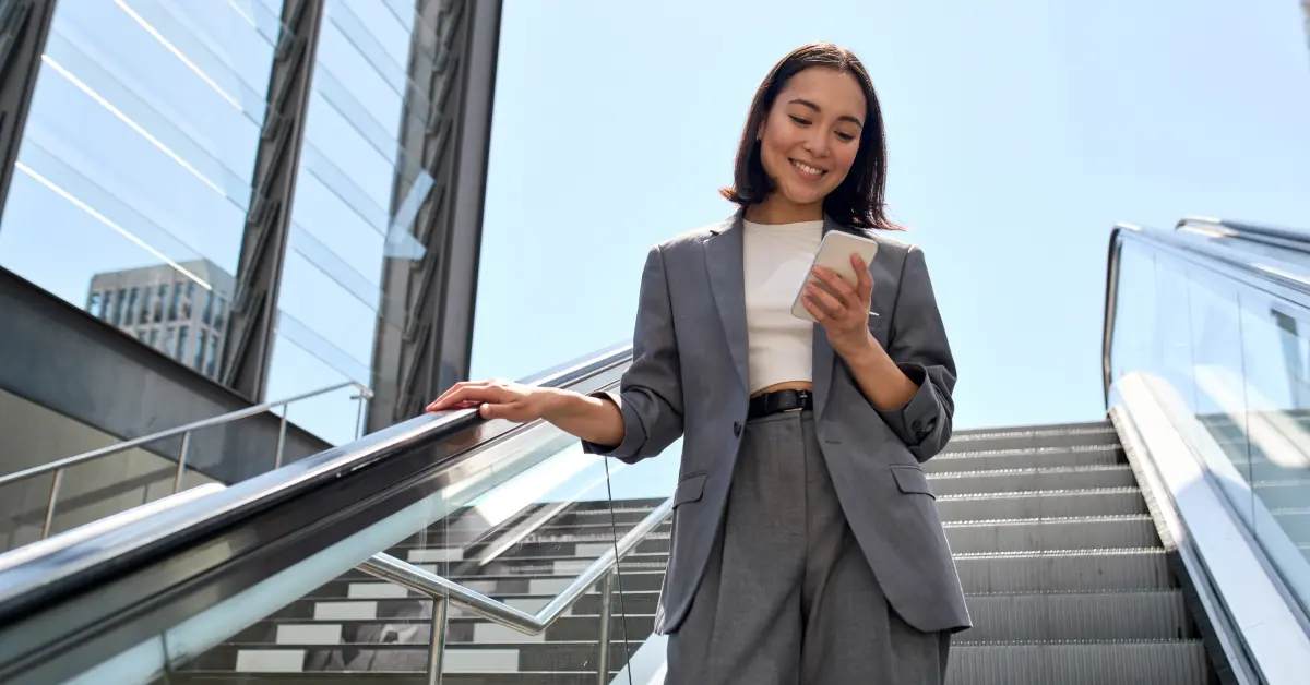 Person walking down stairs, holding phone and smiling.