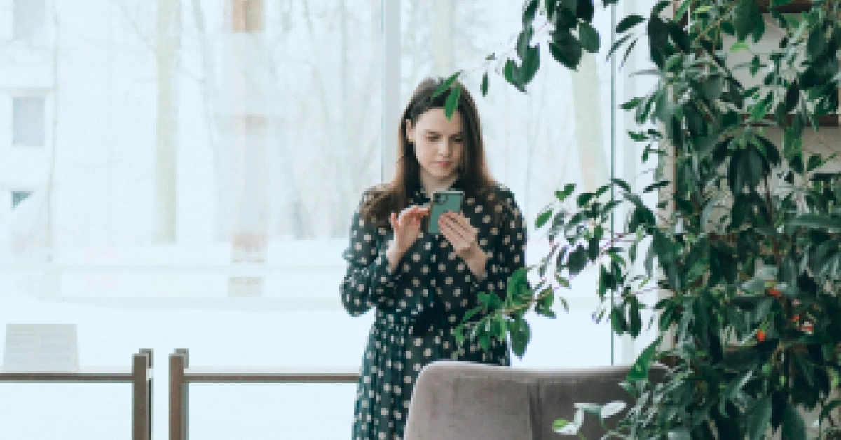 Woman using smartphone near window in office.