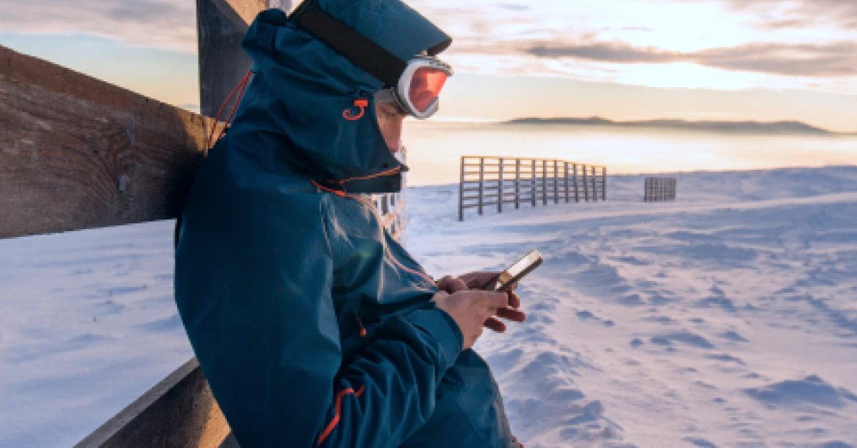 Man leaning on the wooden fence and using smartphone.