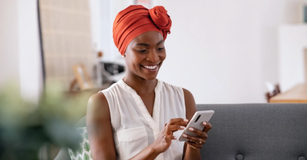 A woman sitting on a couch at home and using a smartphone.