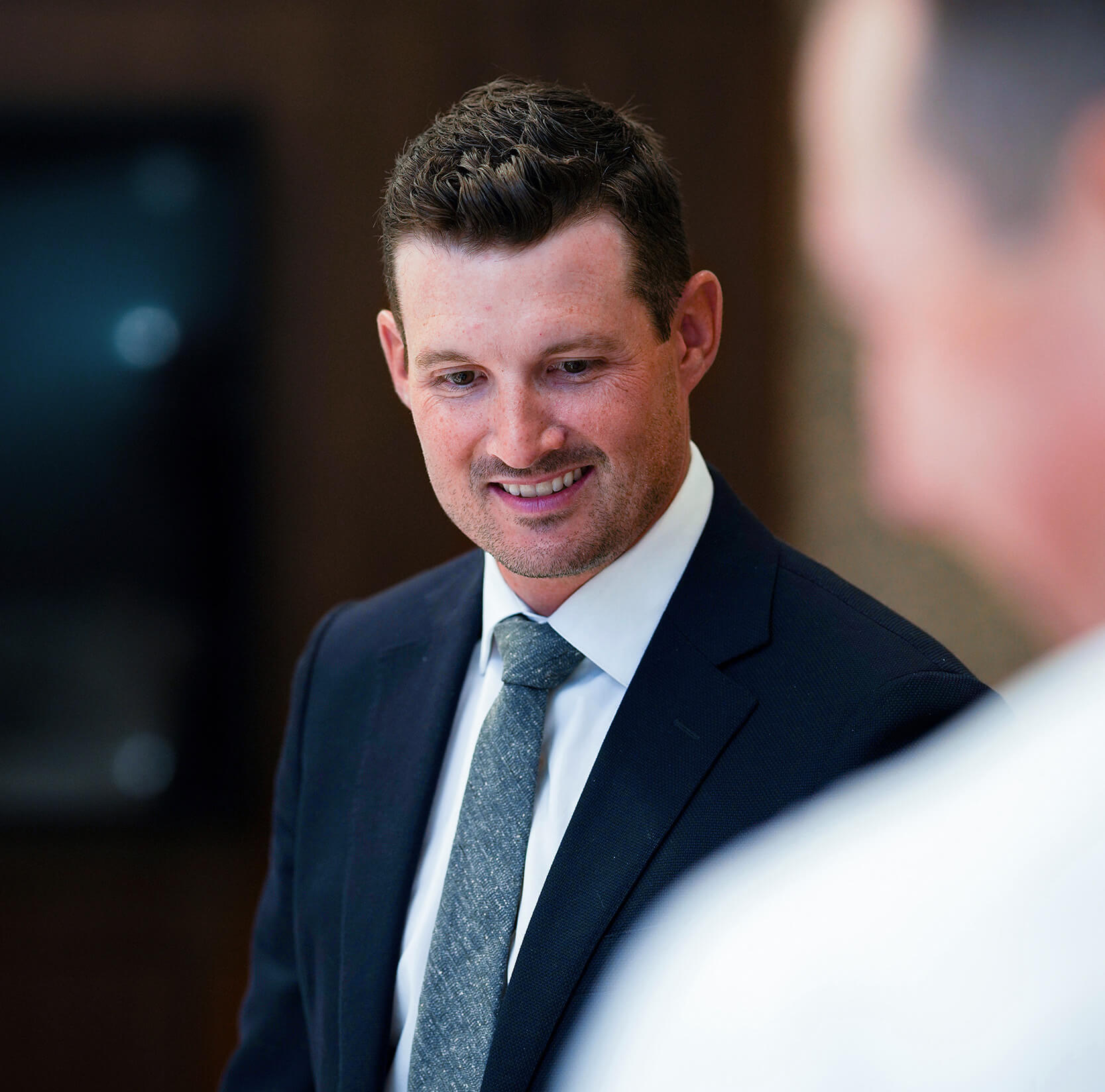 Justin Smith in a suit and tie smiling.