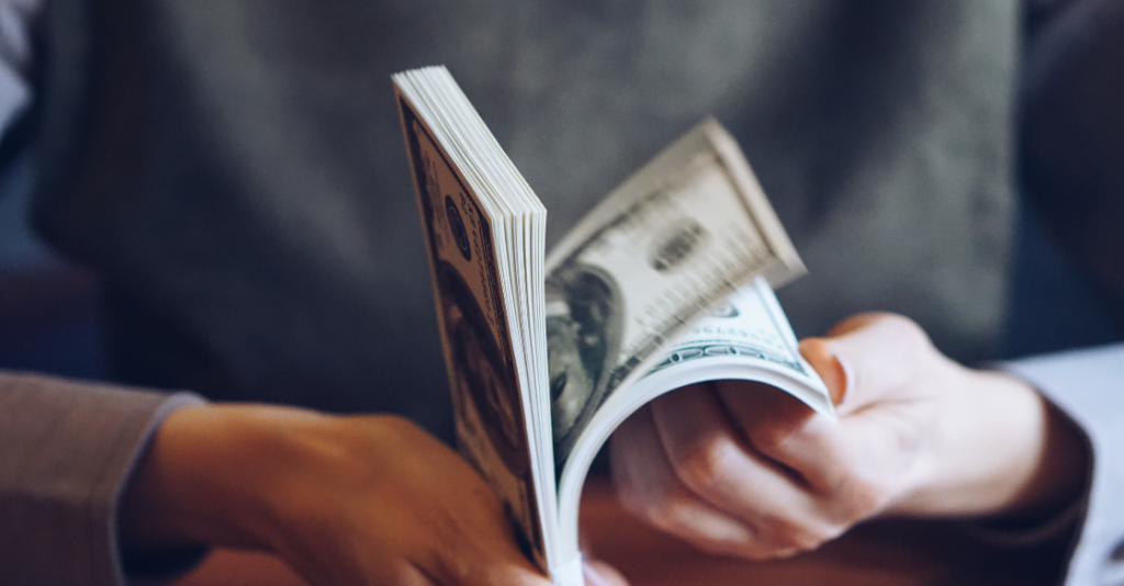 Man holding and fanning multiple $100 bills