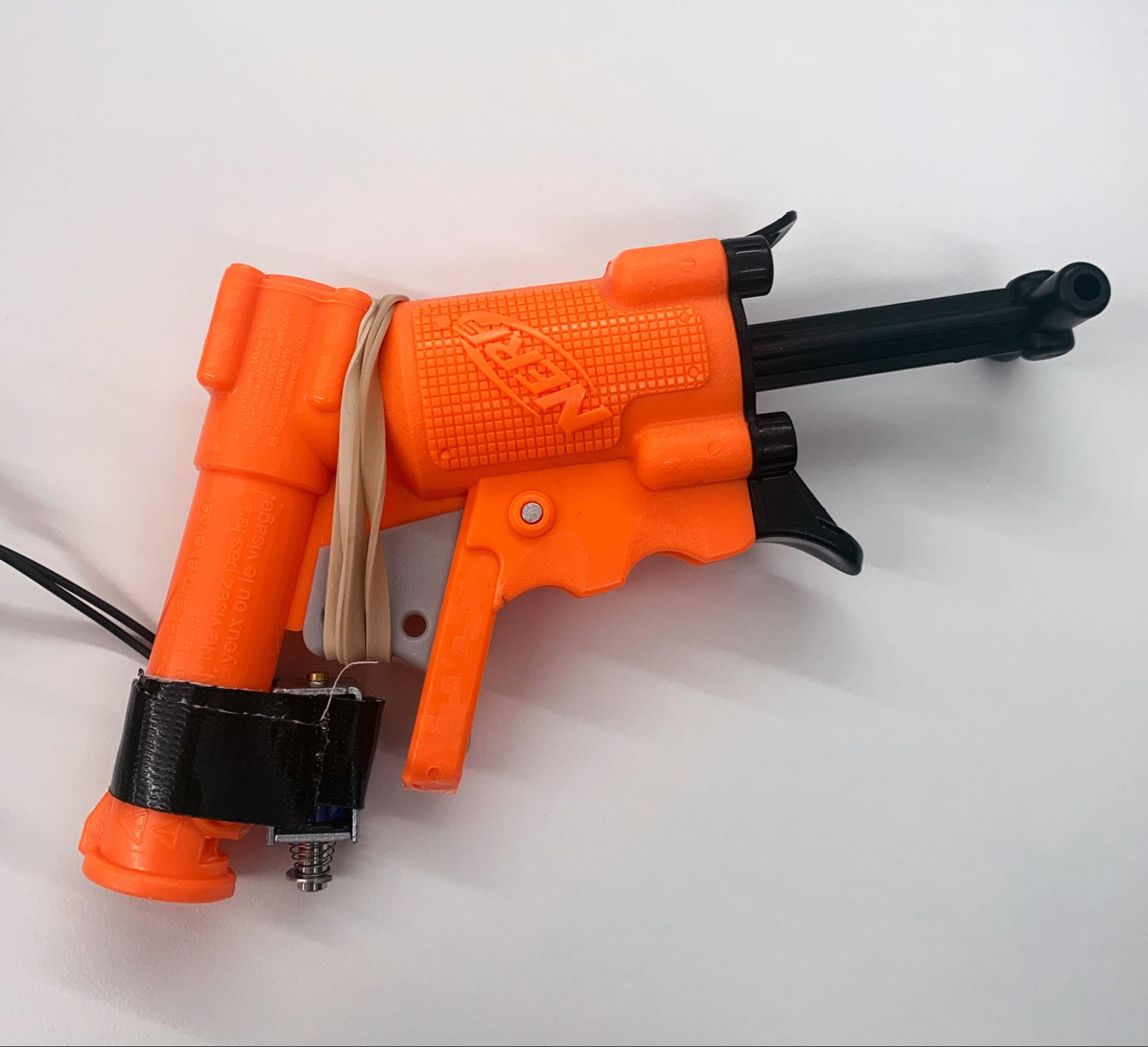 Solenoid attached to the orange foam dart launcher using rubber bands and electrical tape.