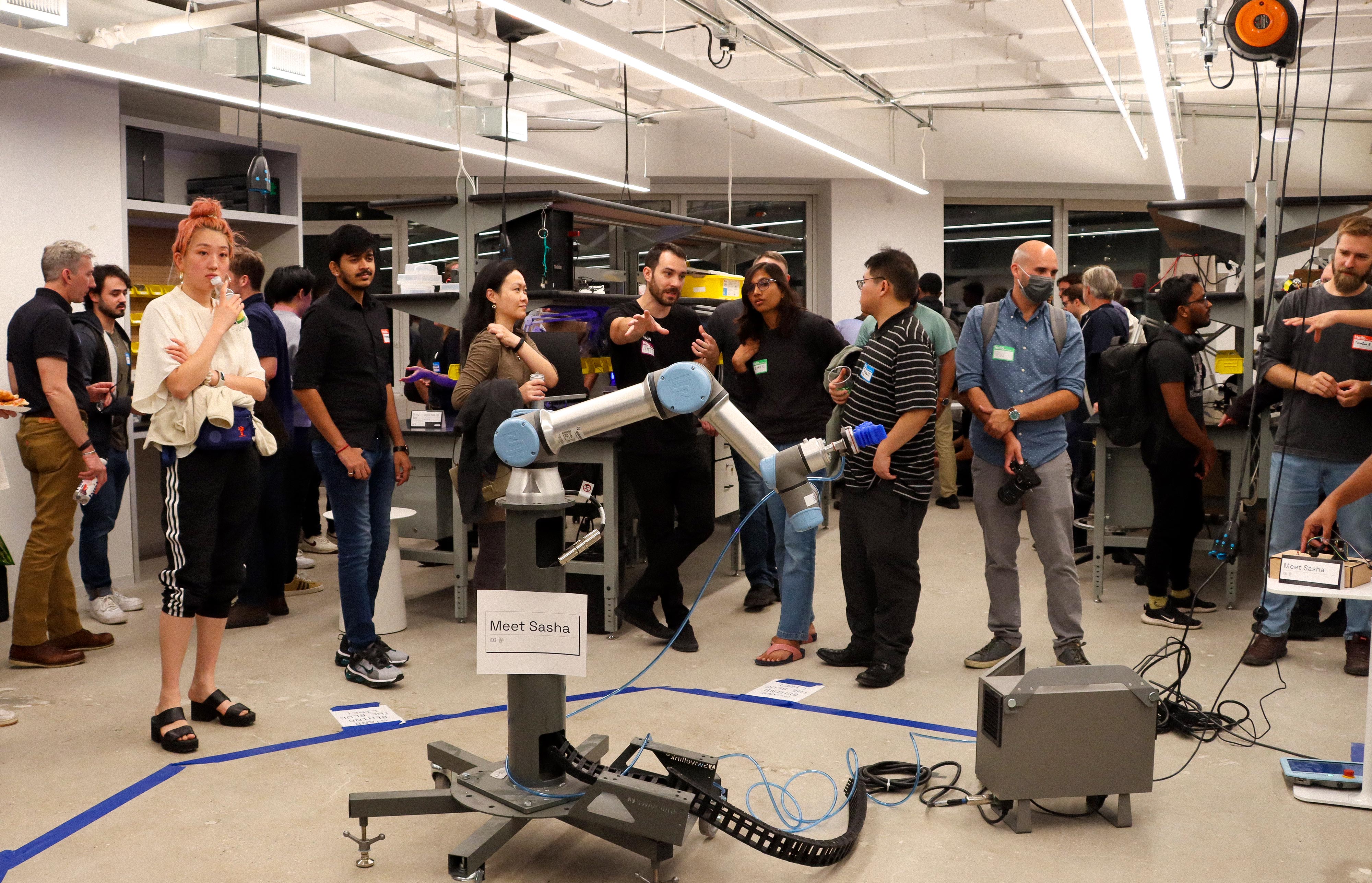 A photo of Viam robotics lab during the NYC Robotics Meetup showing a large group of people gathered around a robot arm. 