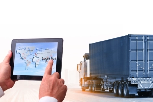 Hands holding a tablet with map, showing behind is a cargo truck