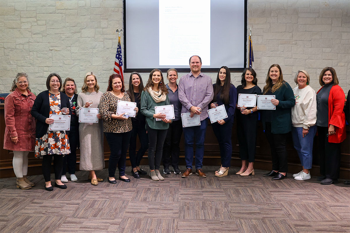 Teachers smile holding certificates.