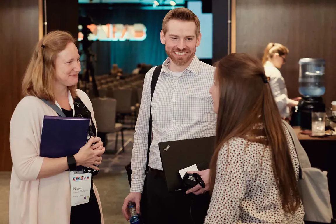 Photo of three happy attendees talking at a break