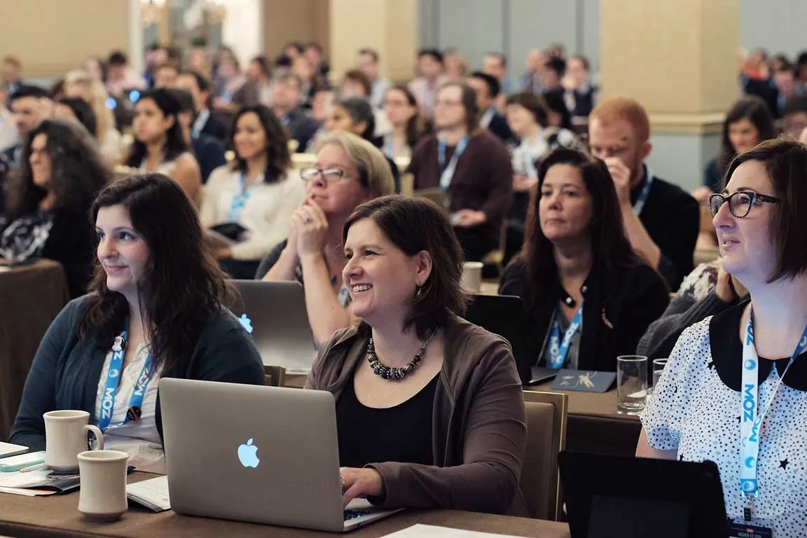 Photo of a crowd of smiling audience members listening to a keynote