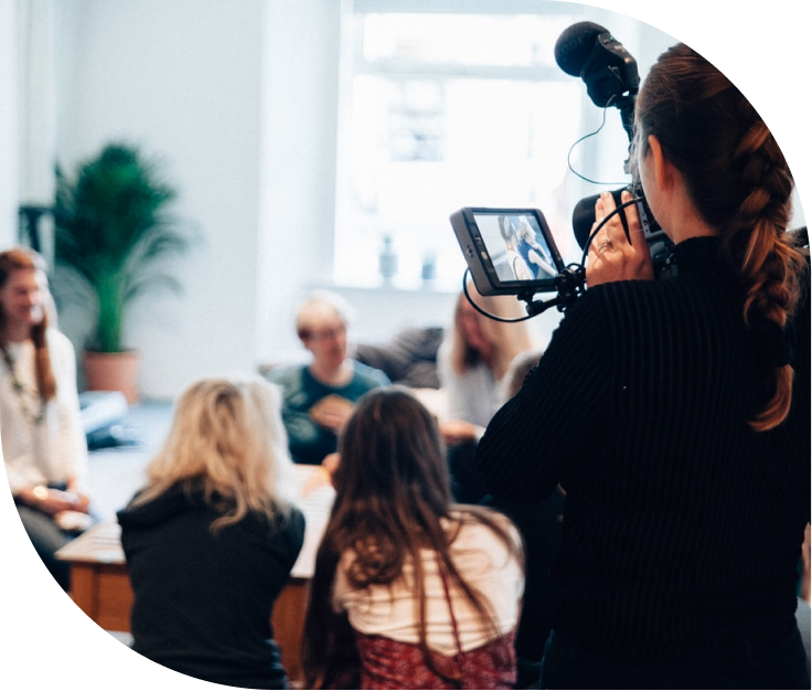 A group of people being filmed by a videographer in an office.