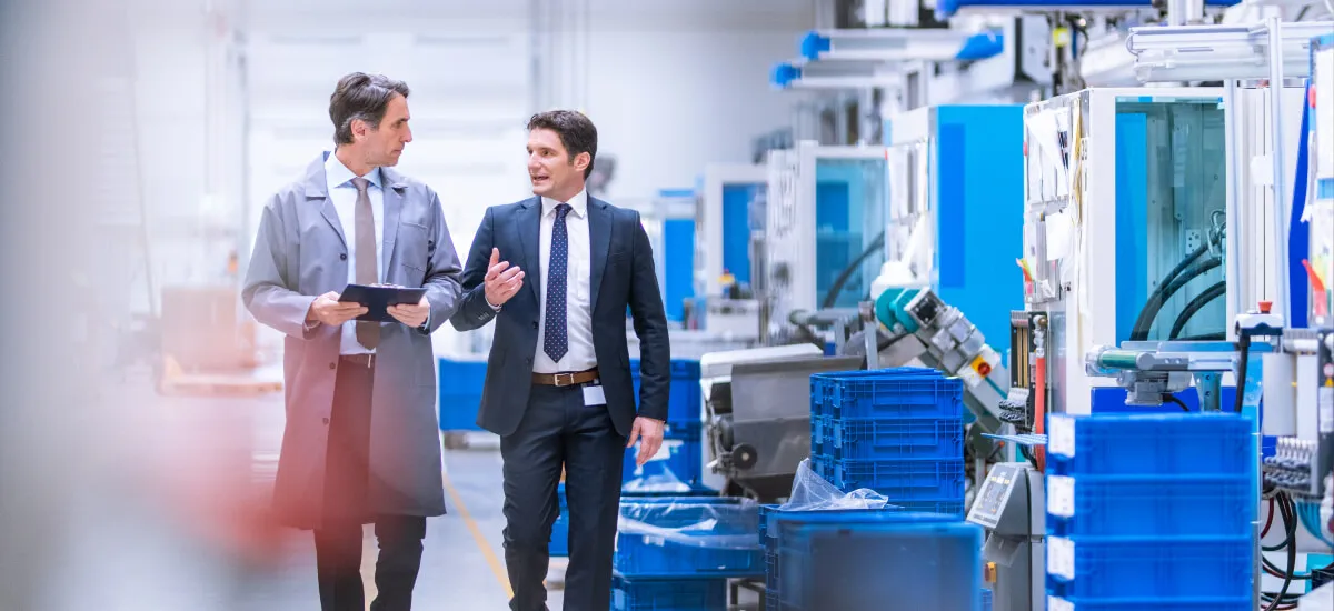 2 men walking through factory