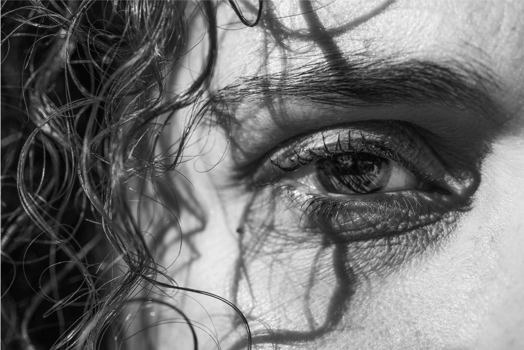 black and white image of a person's eyes with curly hair