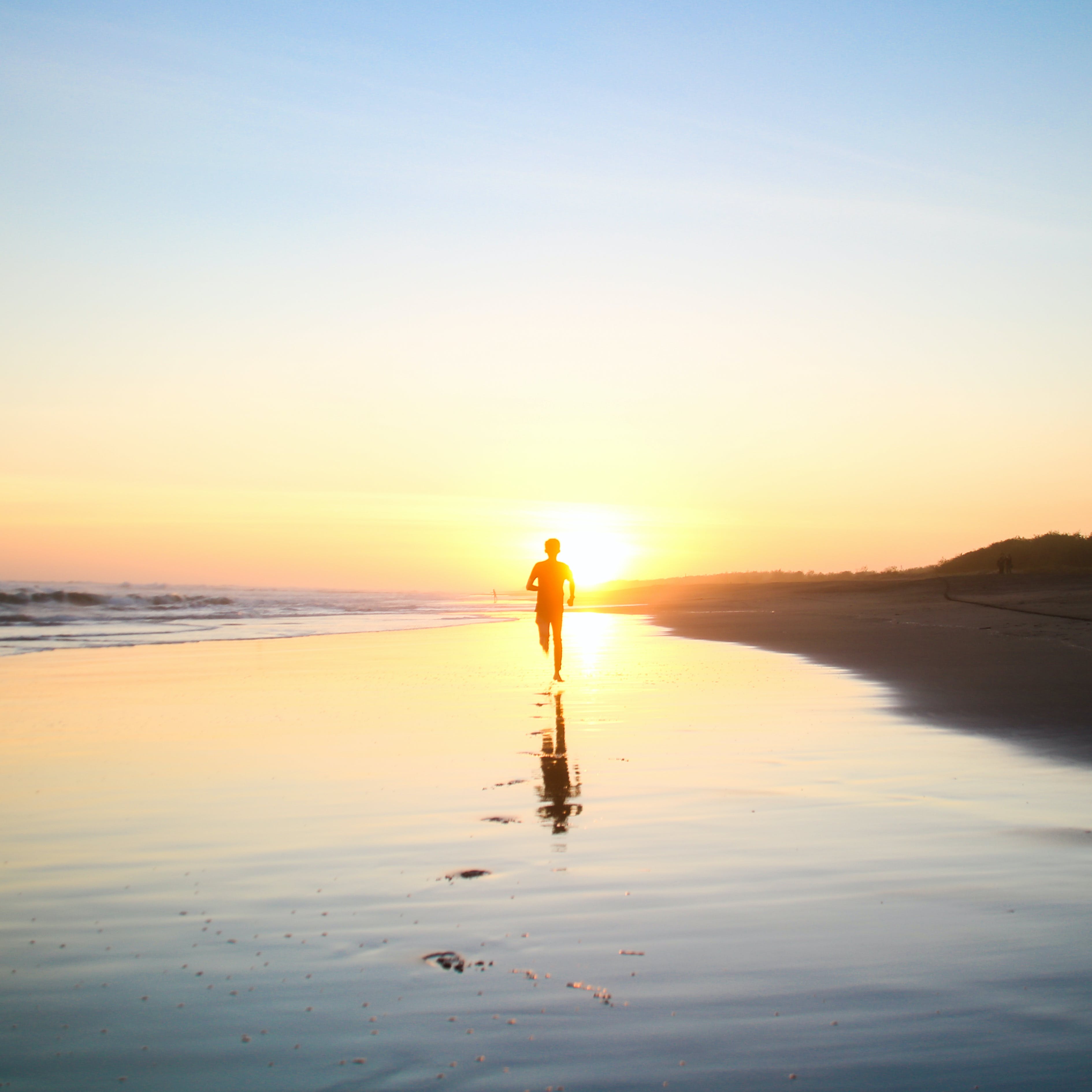 Person running on beach thinking about their wellness journey and life. 