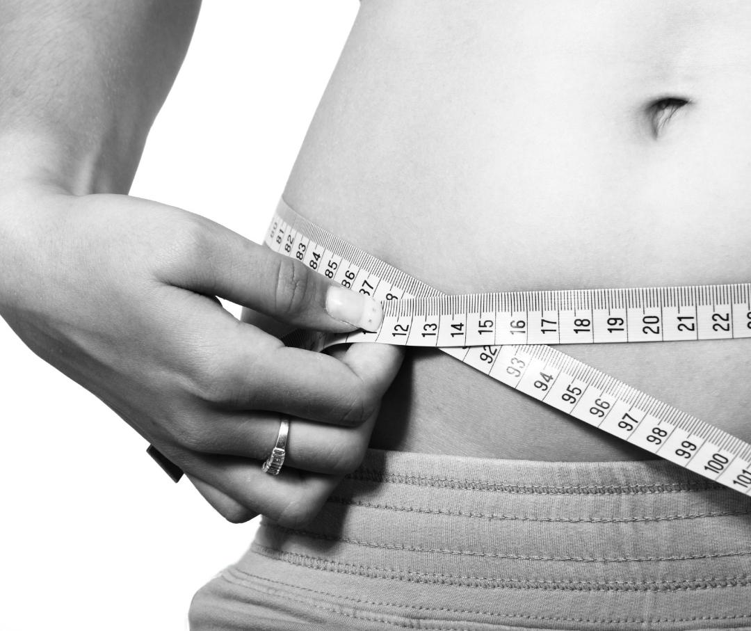 a woman measuring her waist circumference