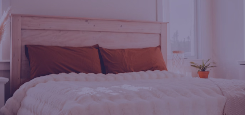 Comfortable bed with plush white comforter and orange pillows