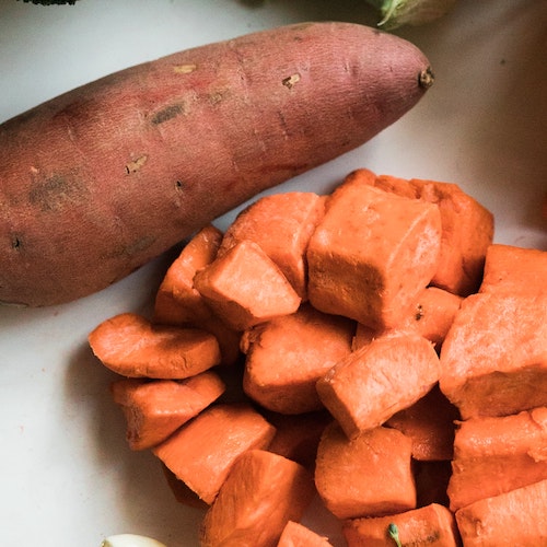 Whole sweet potato next to sweet potato cubes