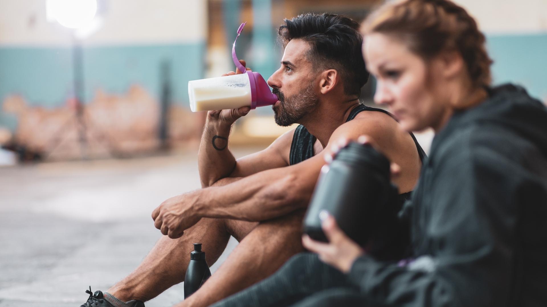 Man and woman drinking protein shake after workout