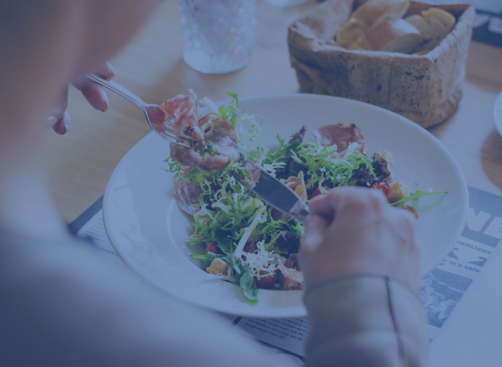 man eating salad with a fork and knife