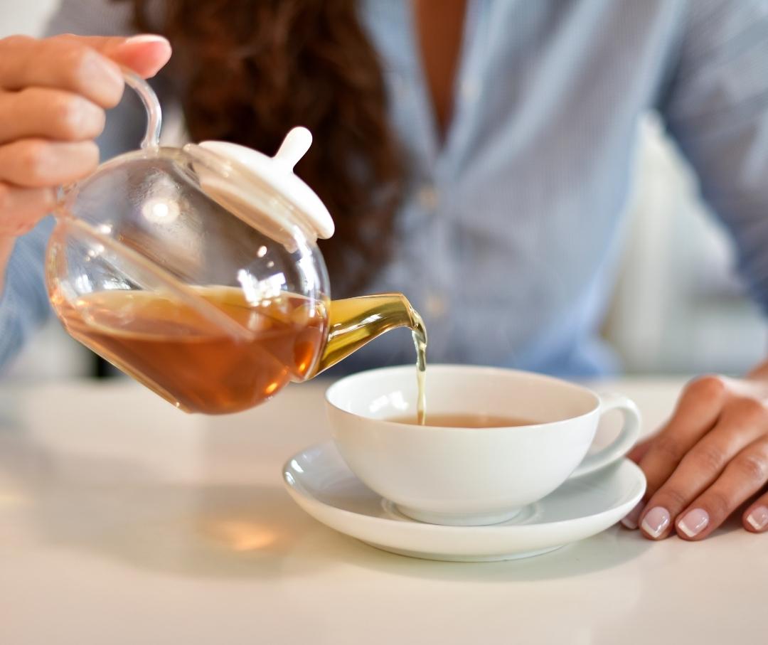 pouring tea into a white mug