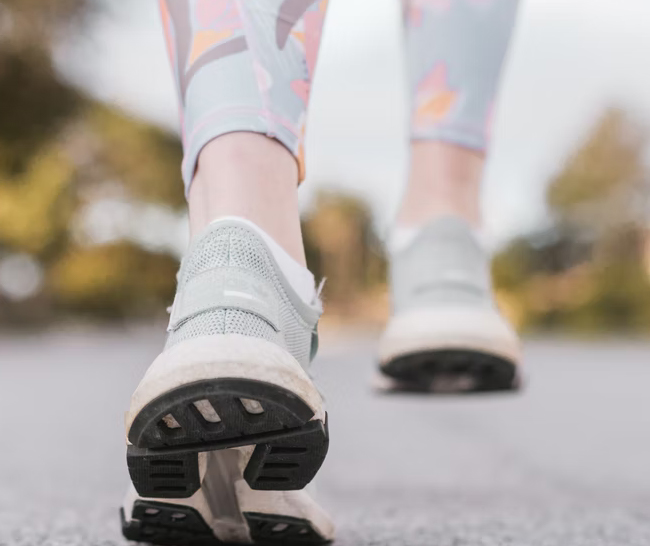 Close up shot of woman's feet, in tennis shoes, walking on a street