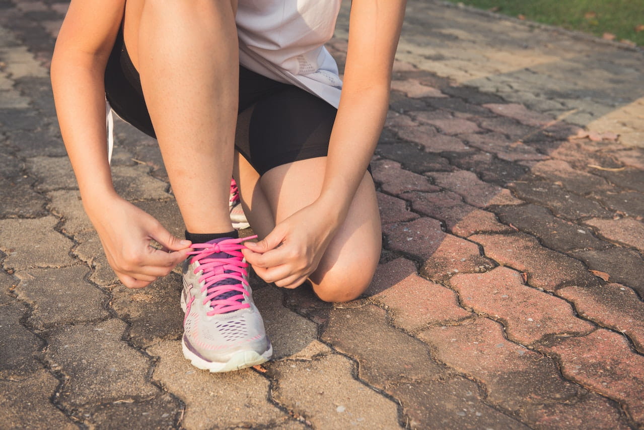 Woman-Lacing-Up-Her-Gray-and-Pink-Nike-Low-top-Athletic-Shoe