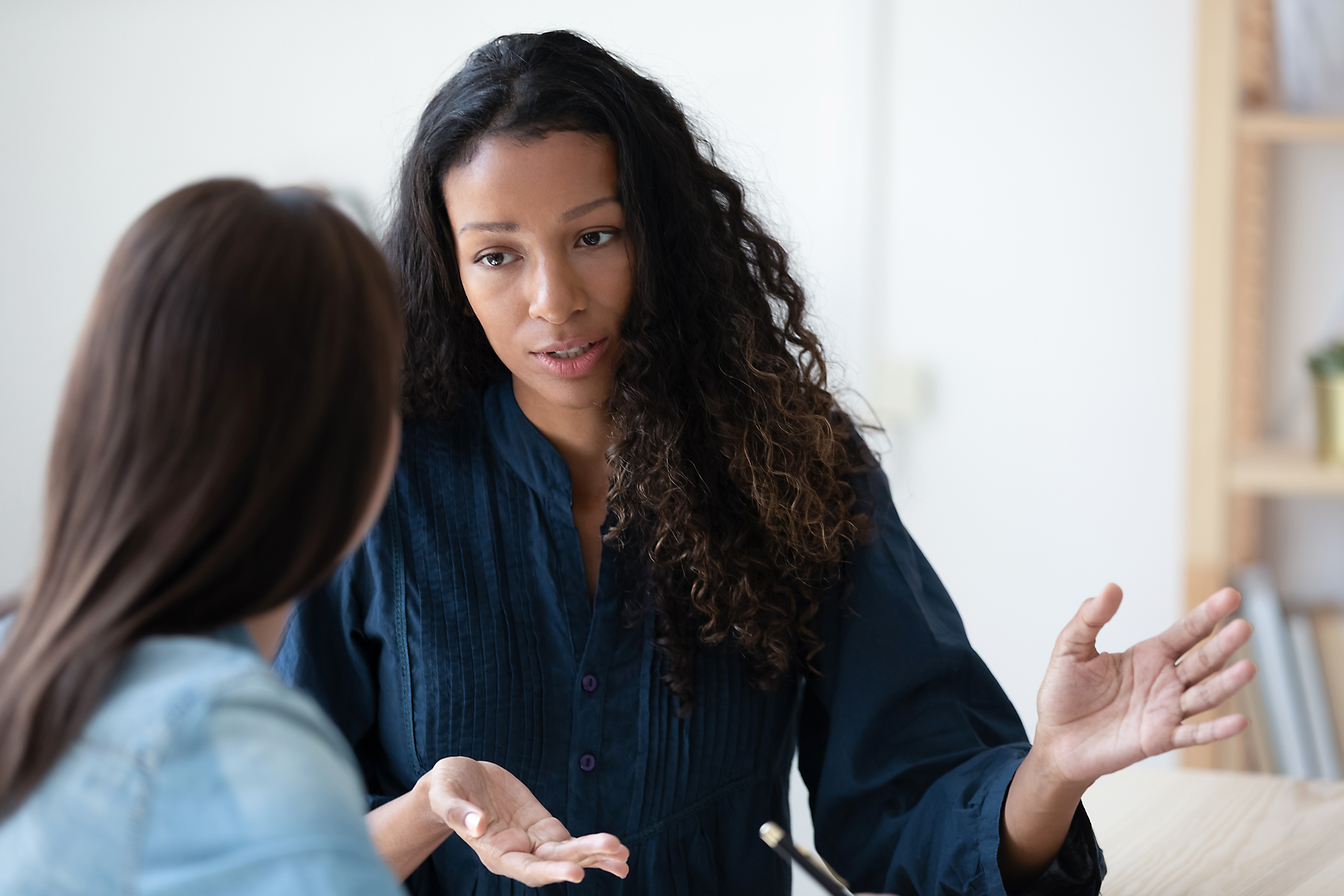 Patient:In bei Therapeut mit Tablet in der Hand.