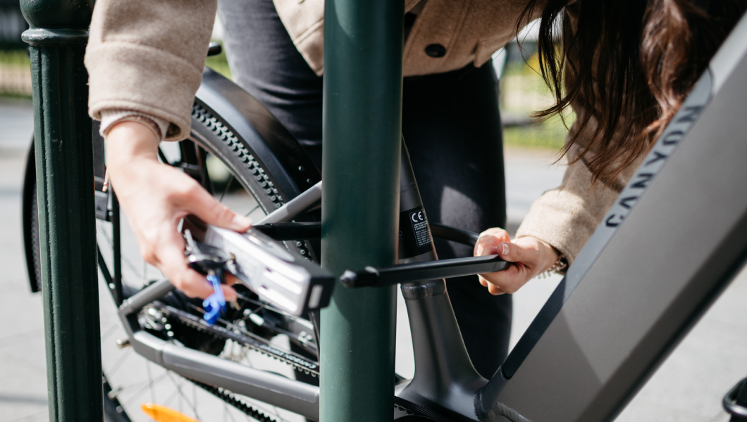 close up of a woman locking a Canyon bike with Qover insurance