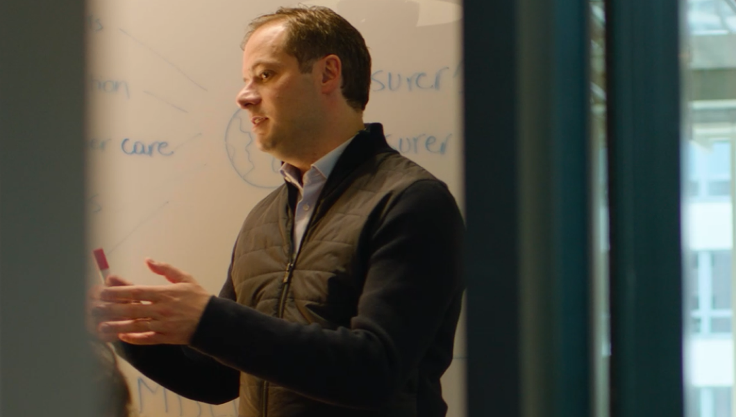 Quentin Colmant explains insurance next to office whiteboard
