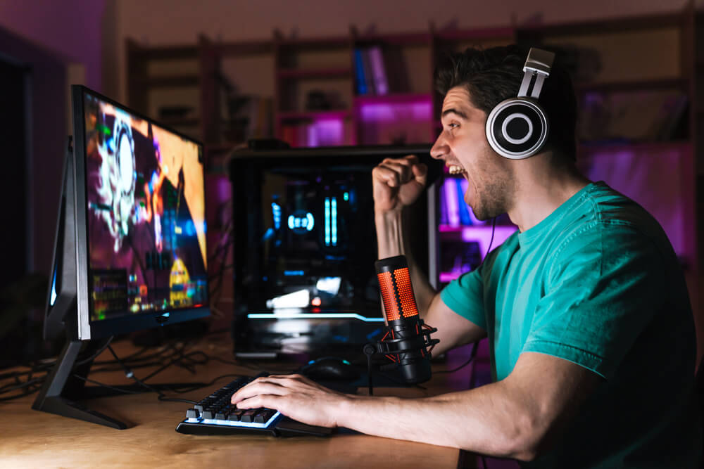 Bearded man playing online video games on his pc and talking with