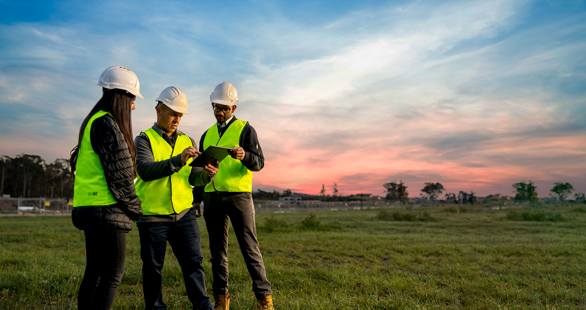 Image of three Orion Consultants in a field looking at an tablet