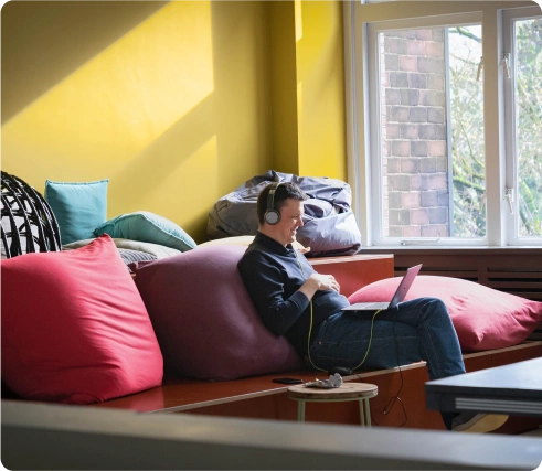 smiling guy sitting on the couch and talking on the computer