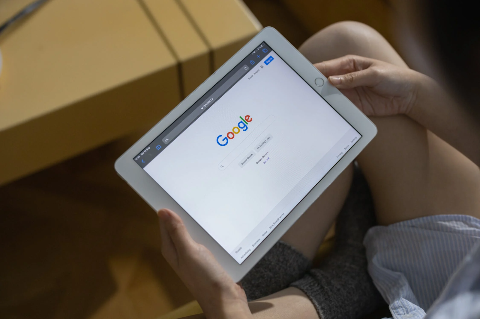 A photo of a person holding an iPad in their hands with Google browser opened