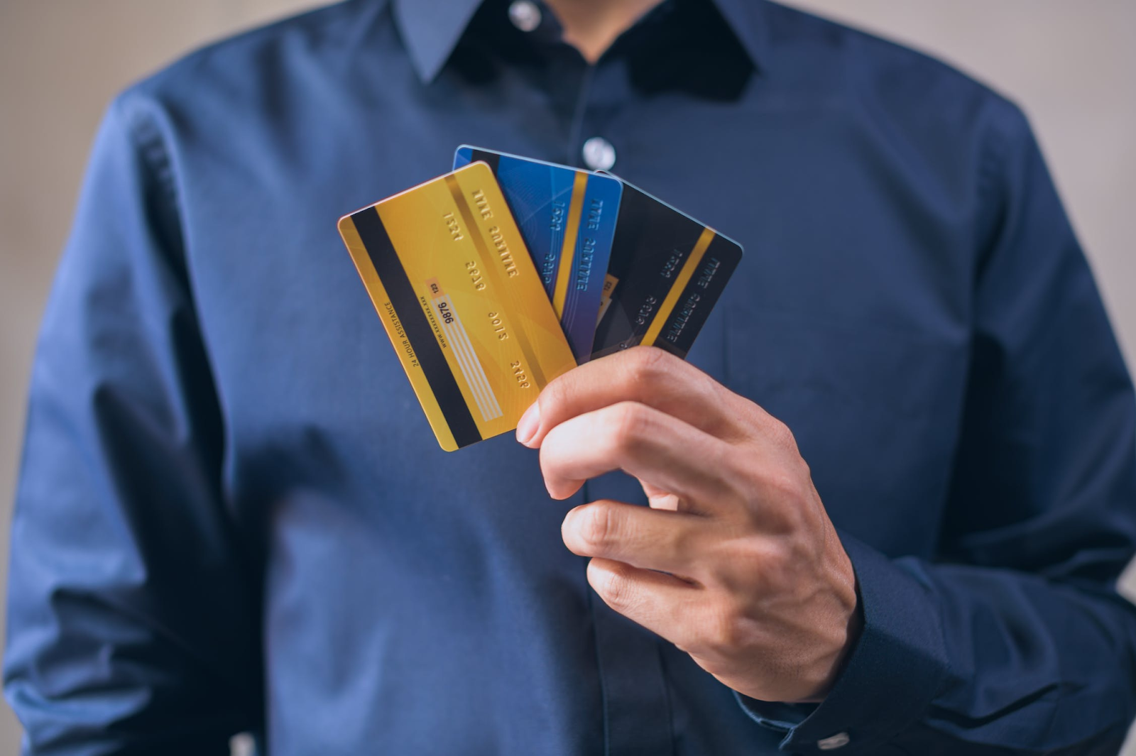 A photo of a man holding three payment cards in his hand