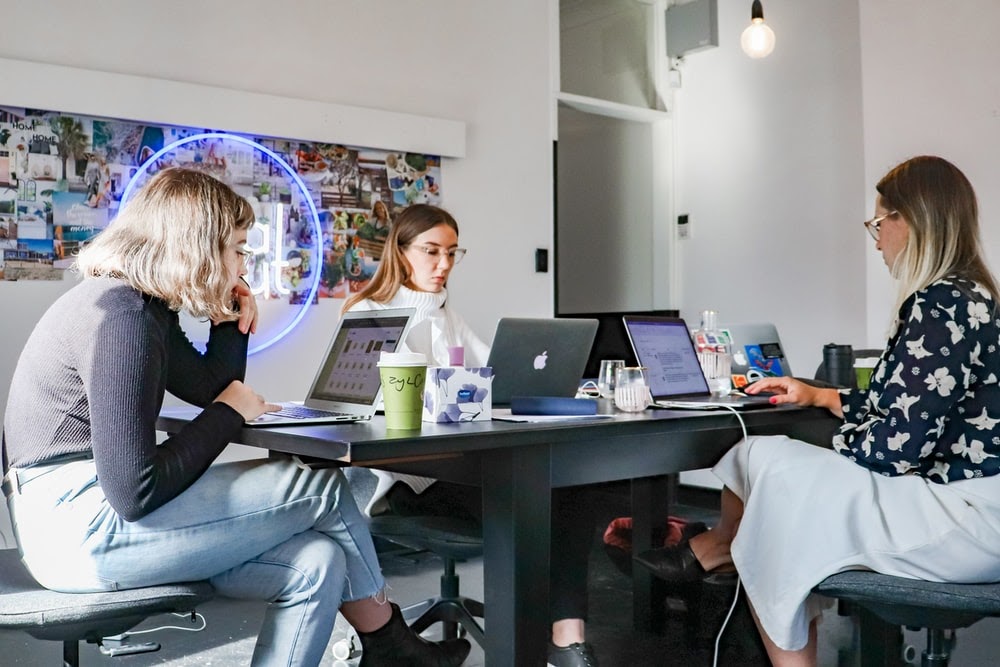 3 people sitting on chair in front of table with laptop computers