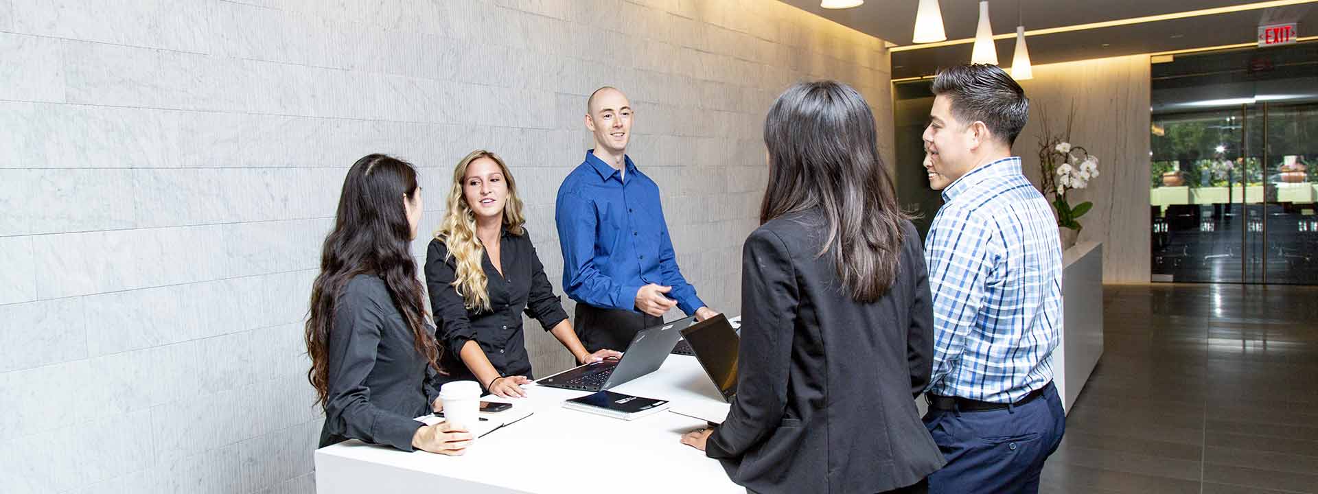 CIM Group Careers | Who We Are - Five CIM employees working around a white marble table in the Los Angeles office