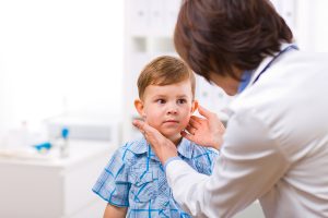 Female doctor examining young boy with strep throat