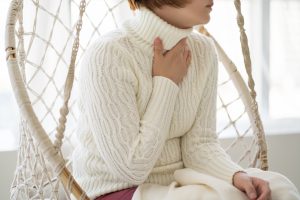 Picture of a woman holding her hand to her throat while she coughs.