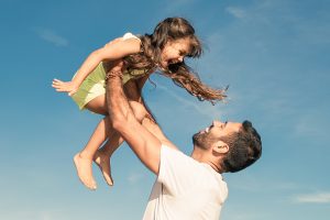Happy young father and daughter playing outside