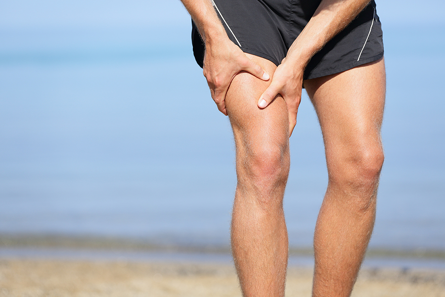 Man holding his upper leg in pain from a muscle strain