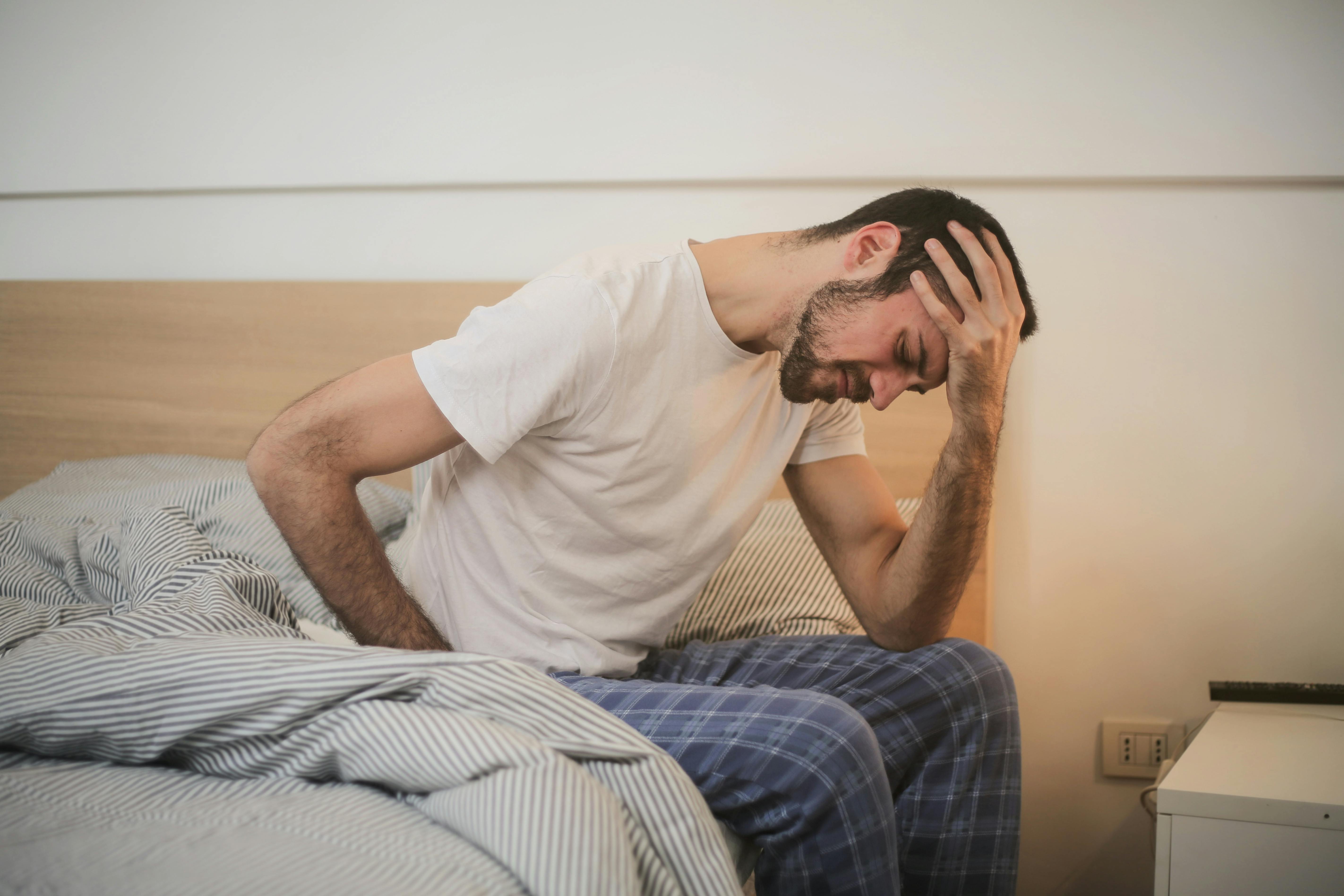 Picture of a sick man sitting on side of bed