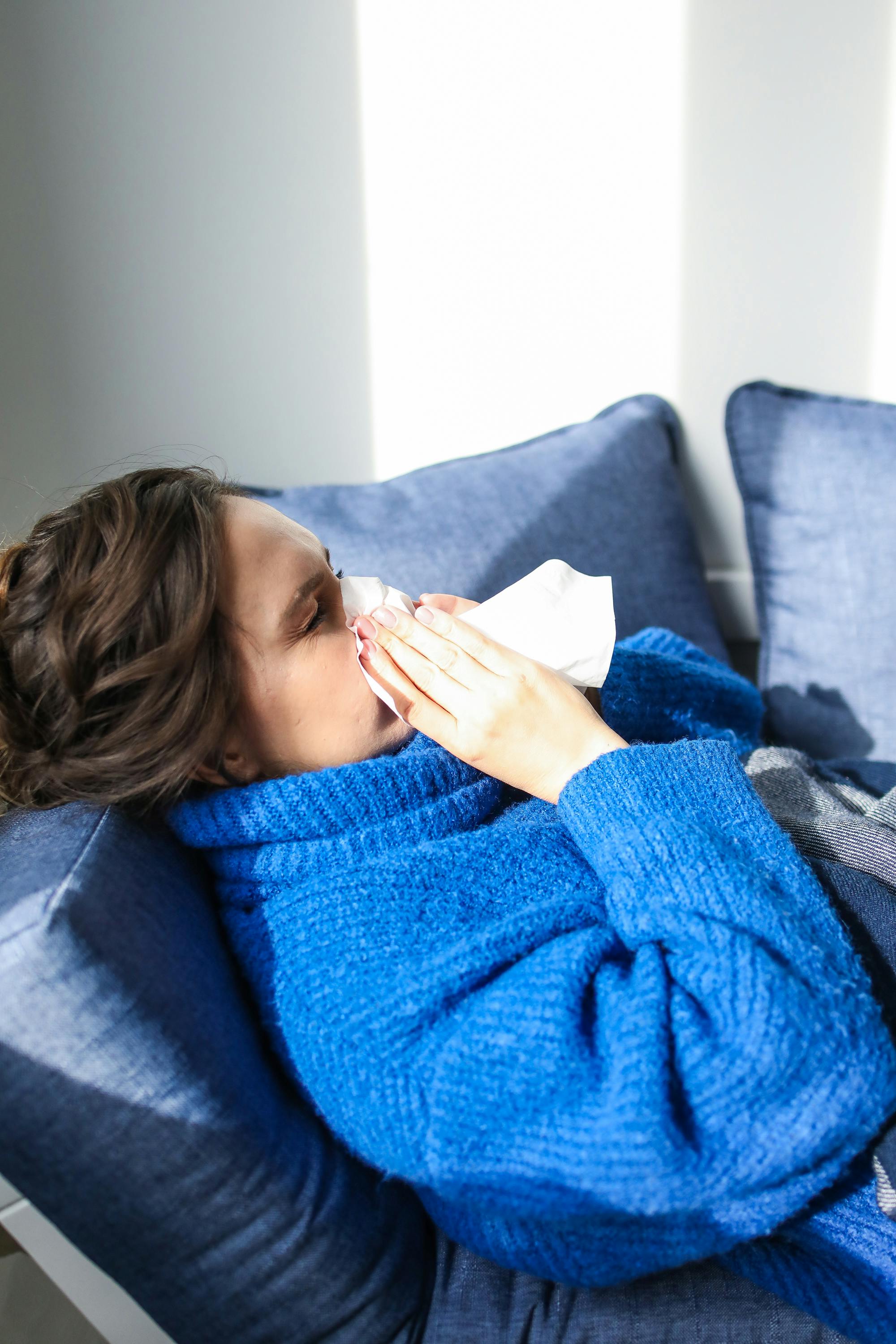 woman on couch blowing her nose
