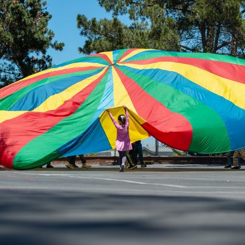 Kids playing with a rainbow parachute