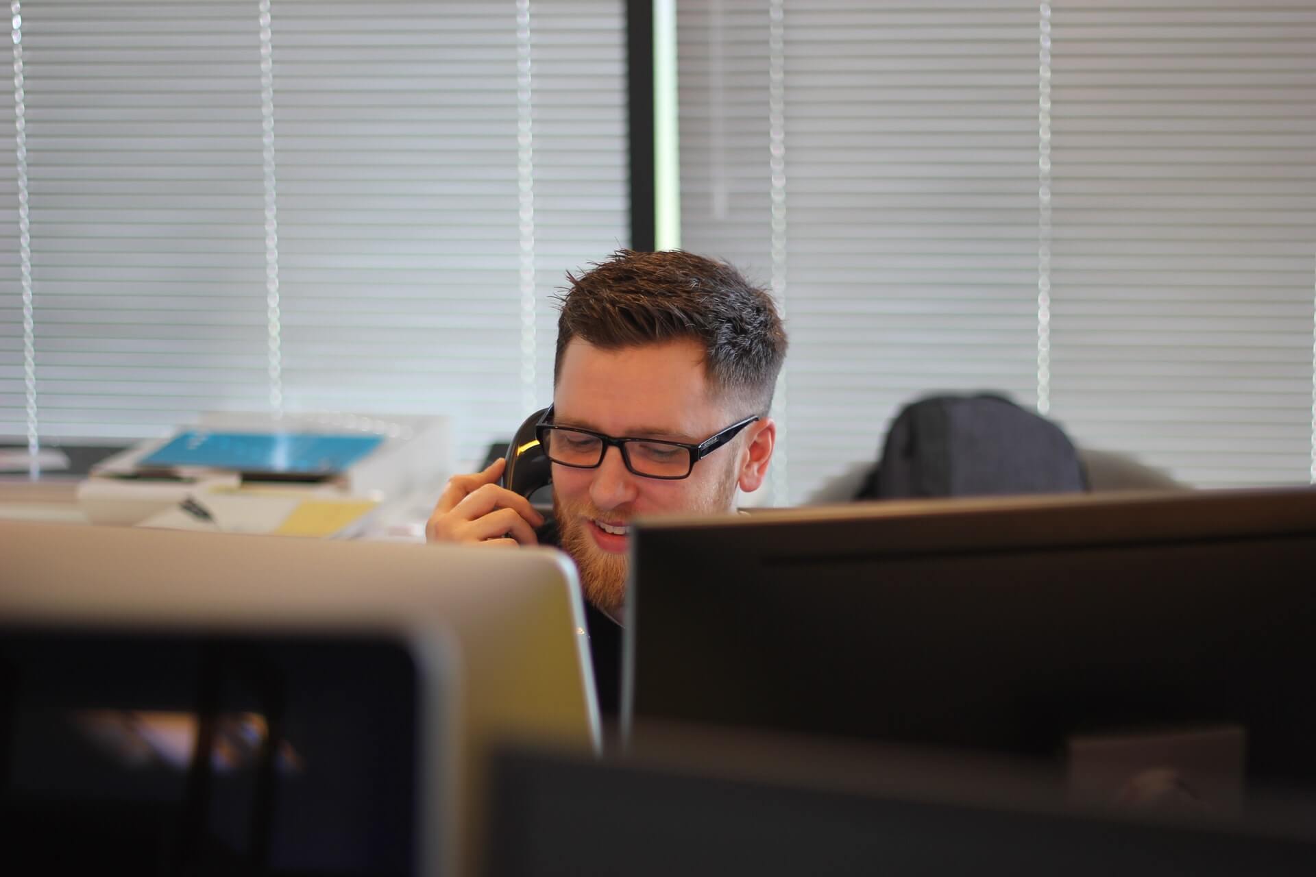 man on the phone while in front of two screens 