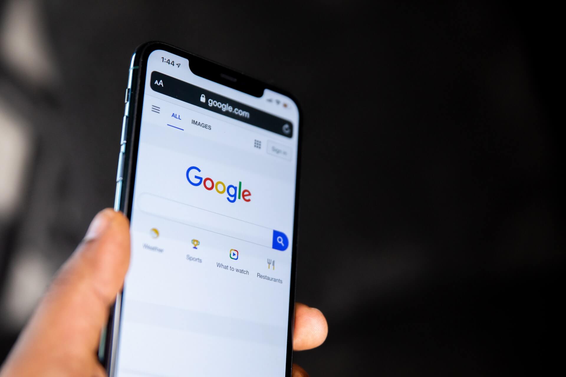 hand holding a mobile with google search on the screen