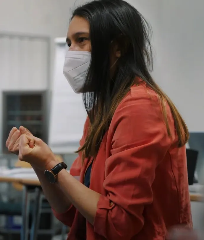 Eine Kursleiterin mit Maske erklärt gestikulierend