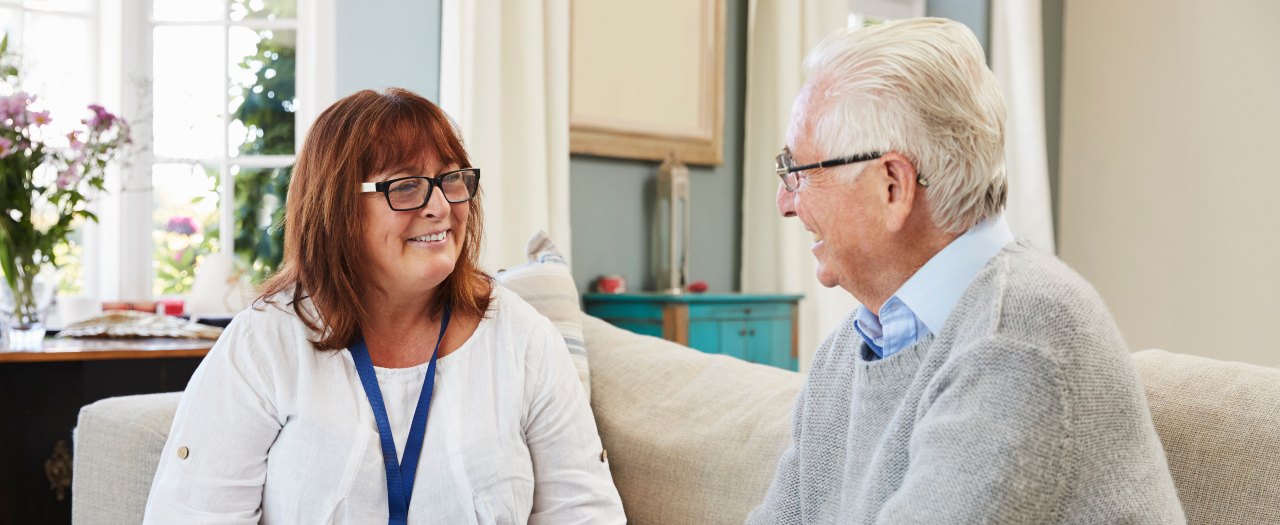 geriatric nursing assistant sitting with a patient