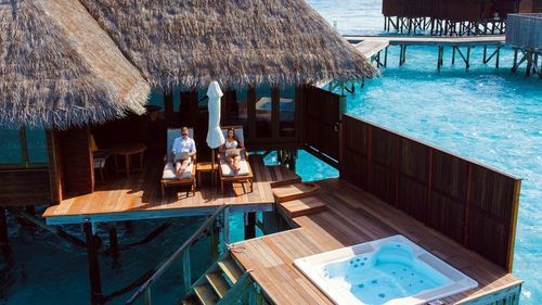 Couple working on laptop in resort with clear blue water