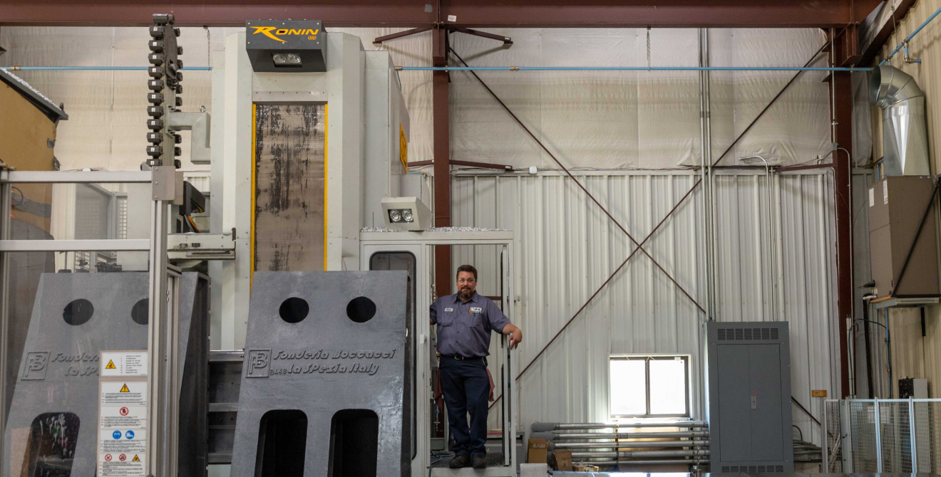 A person standing on platform of large horizontal milling machine.